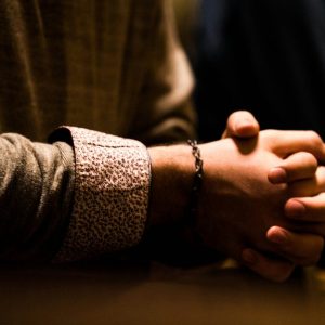 two people holding hands while sitting at a table
